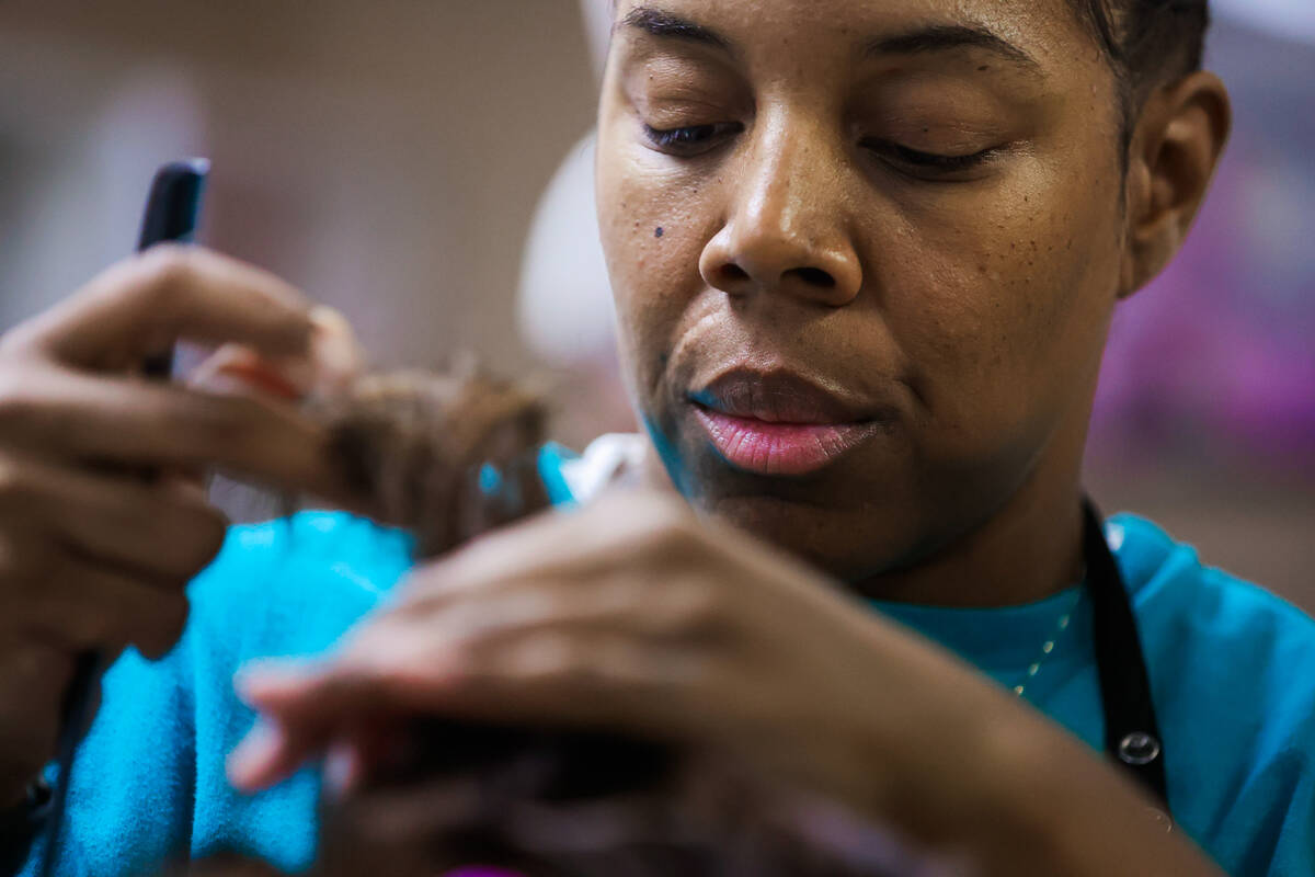 Majunique Brown combs out hair on a mannequin’s head during a cosmetology class at Flore ...