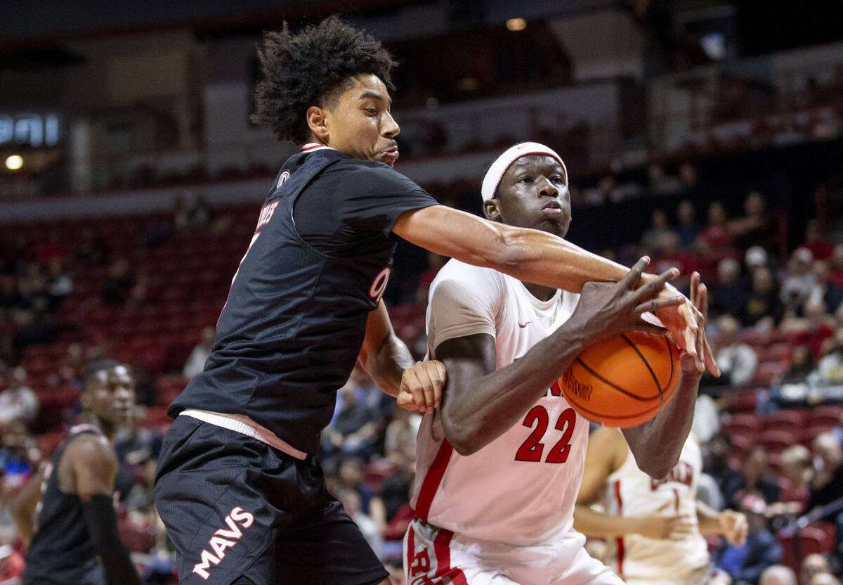 Omaha Mavericks guard Lance Waddles, left, swats the ball from UNLV forward Pape N'Diaye (22) d ...