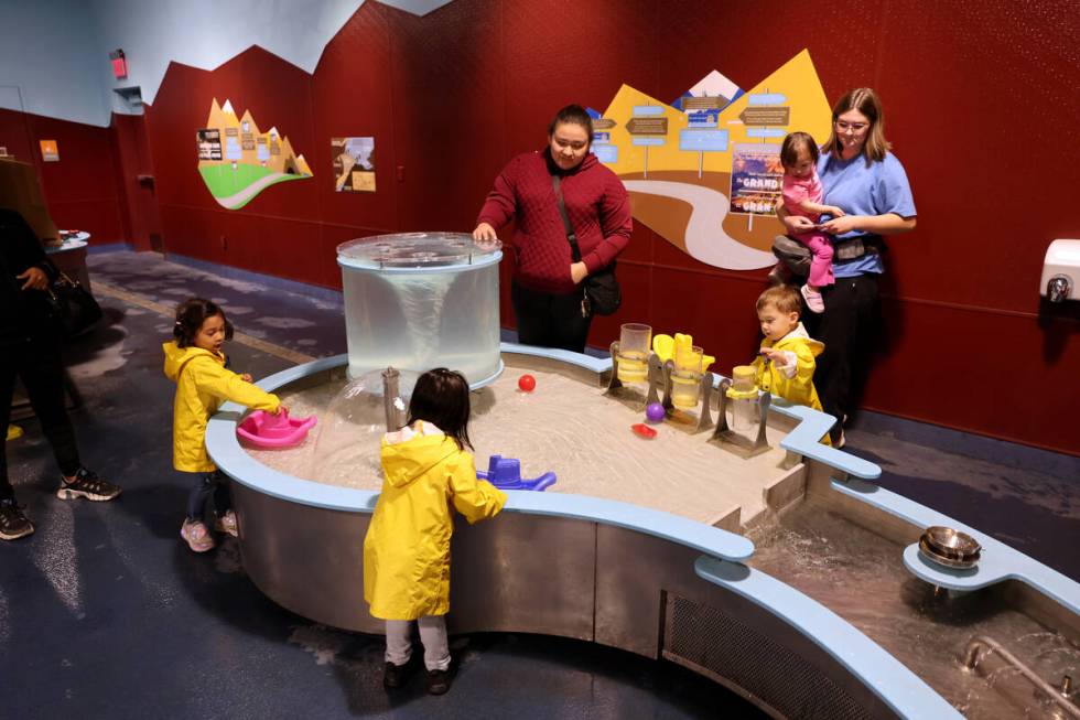 Parents and children explore the ‘Water World’ exhibit at Discovery Children’s Museum in ...