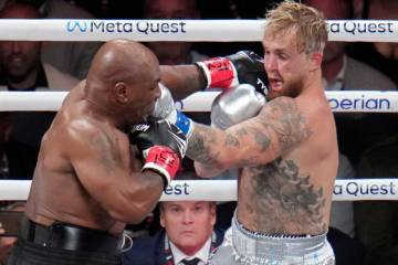 Mike Tyson hits Jake Paul during their heavyweight boxing match, Friday, Nov. 15, 2024, in Arli ...