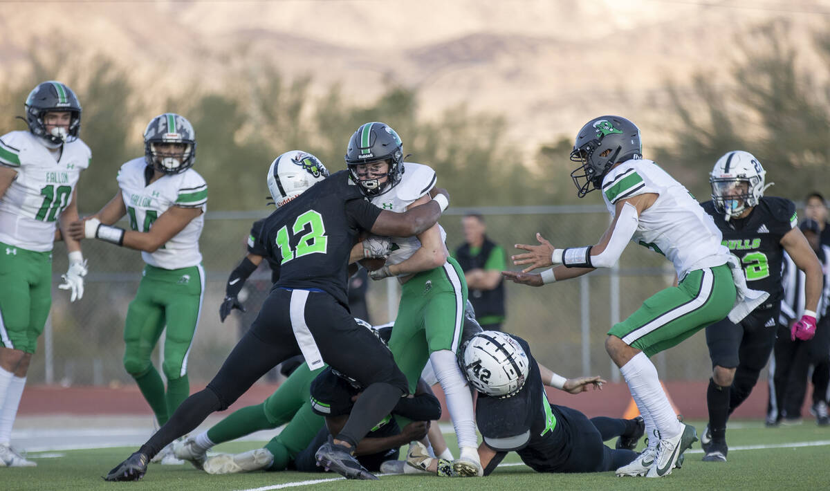 SLAM Academy senior Damien Nevil, left, tackles Churchill County junior Carson Melendy, right, ...