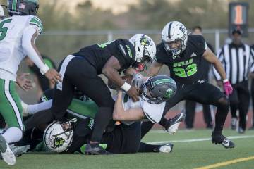 SLAM Academy senior Damien Nevil, left, tackles Churchill County junior Carson Melendy, right, ...