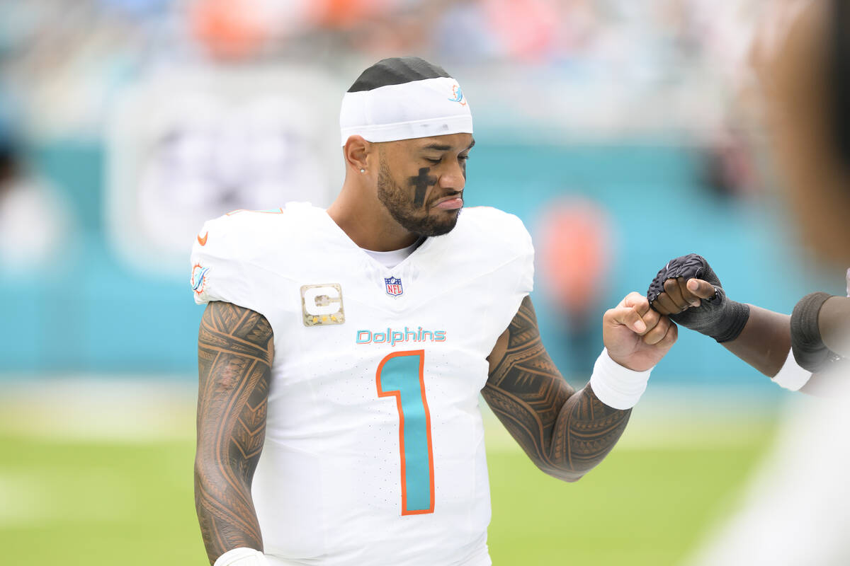 Miami Dolphins quarterback Tua Tagovailoa (1) bumps fists with a player on the sidelines before ...