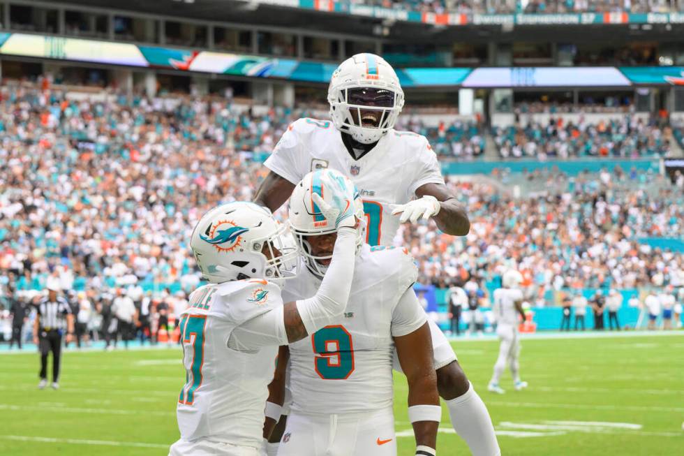 Miami Dolphins wide receiver Tyreek Hill (10) jumps on top of tight end Jonnu Smith (9) as Hill ...