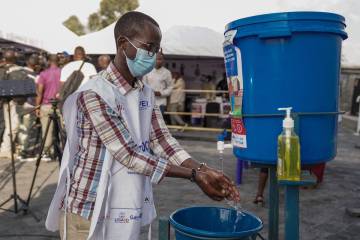 A social mobilizer washes up in preparation to help receive members of the community ahead of t ...