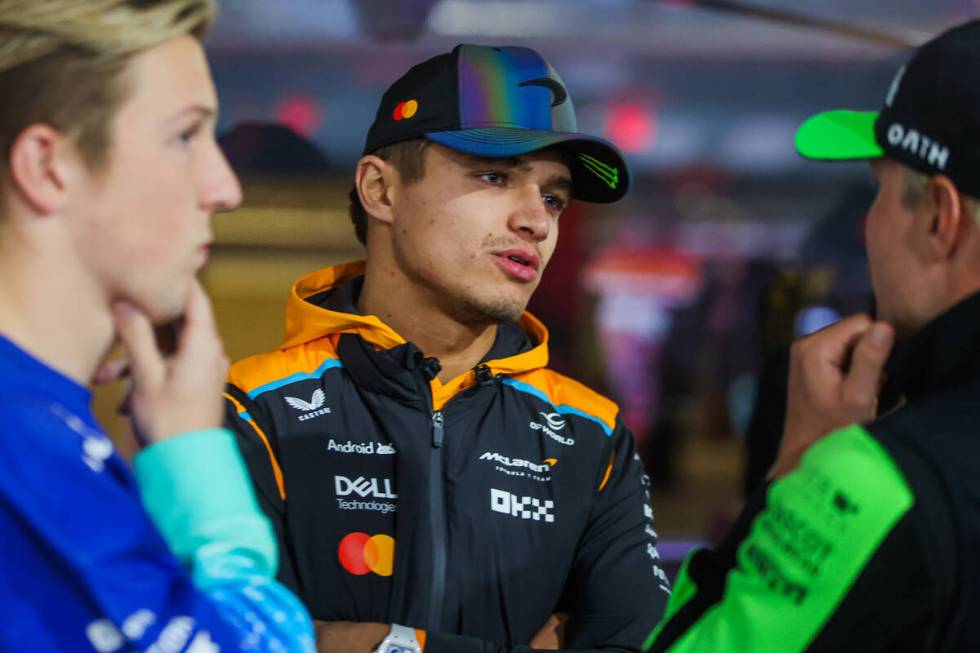 Formula 1 driver Lando Norris chats with other drivers as he gets ready to speak at a press con ...