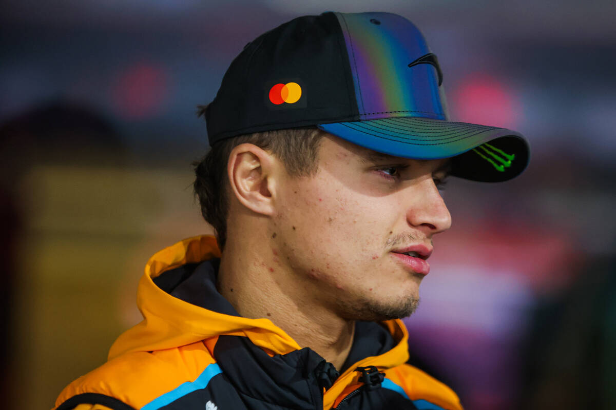 Formula 1 driver Lando Norris chats with other drivers as he gets ready to speak at a press con ...