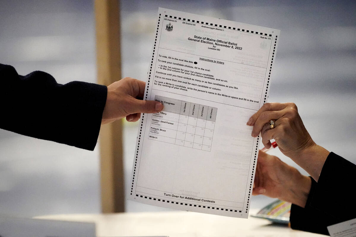 A ballot showing the choices for Maine's 2nd Congressional District is handed to a voter in Lew ...