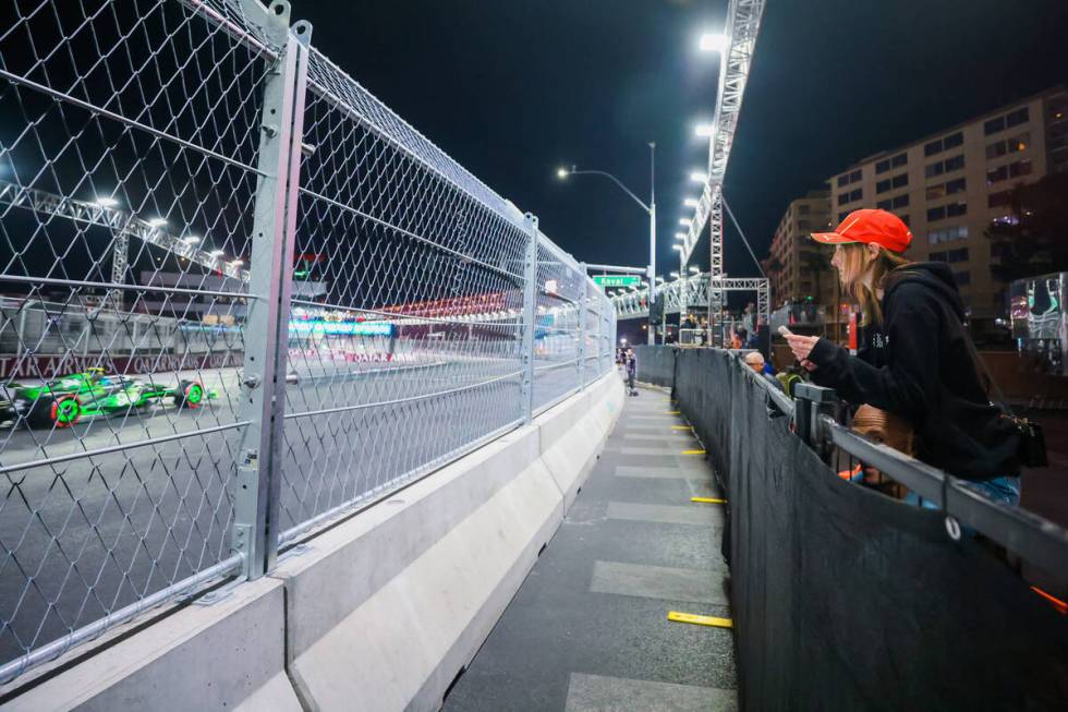 Formula 1 fan Maya Nypl of Paradise, Calif., is hoisted over a barrier to sneak a peek of drive ...