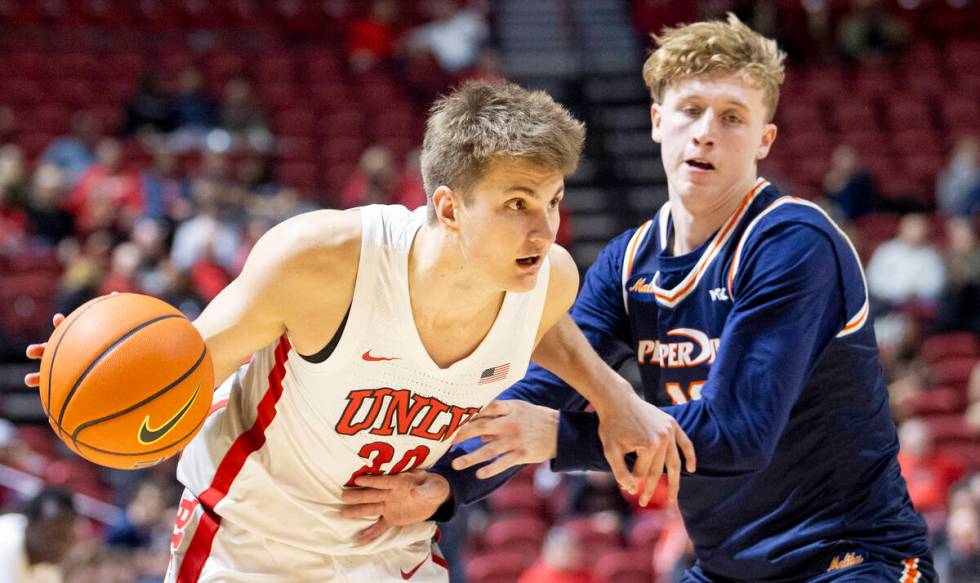 UNLV guard Julian Rishwain (20) attempts to dribble around Pepperdine Waves guard Jaxon Olvera, ...