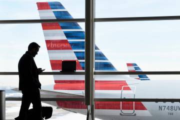 A passenger talks on the phone with American Airlines jets parked behind him at Washington's Ro ...