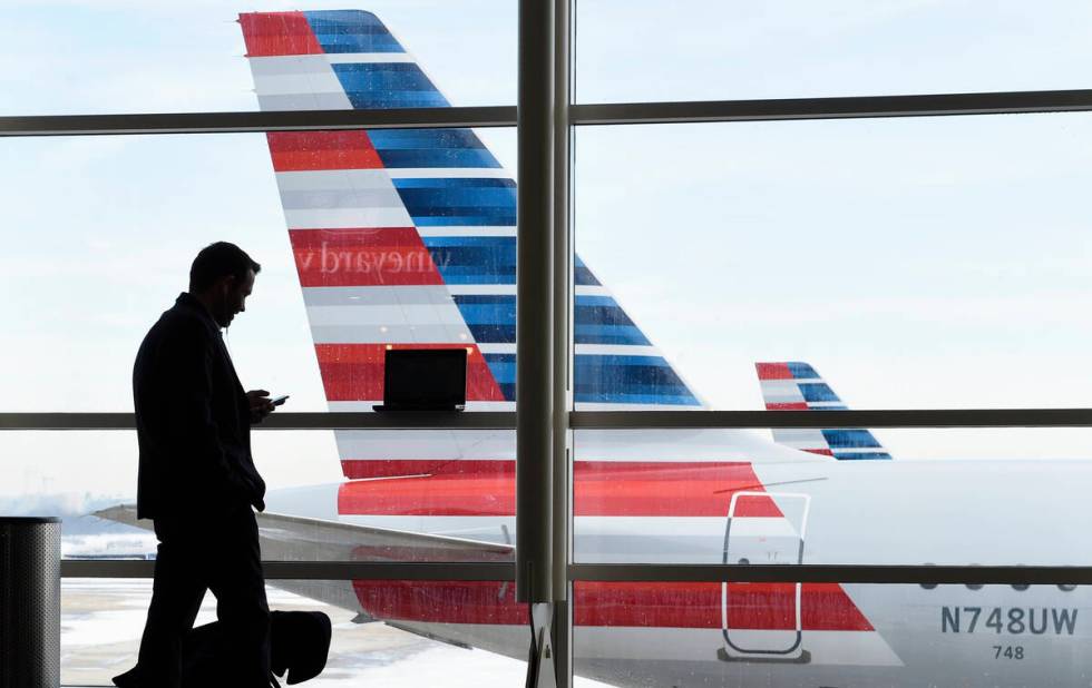 A passenger talks on the phone with American Airlines jets parked behind him at Washington's Ro ...