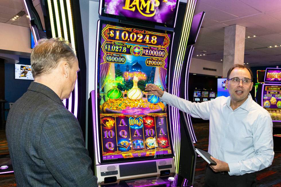 IGT's Nick Khin, right, demonstrates how Mystery of the Lamp game is played on IGT PeakCurve49 ...