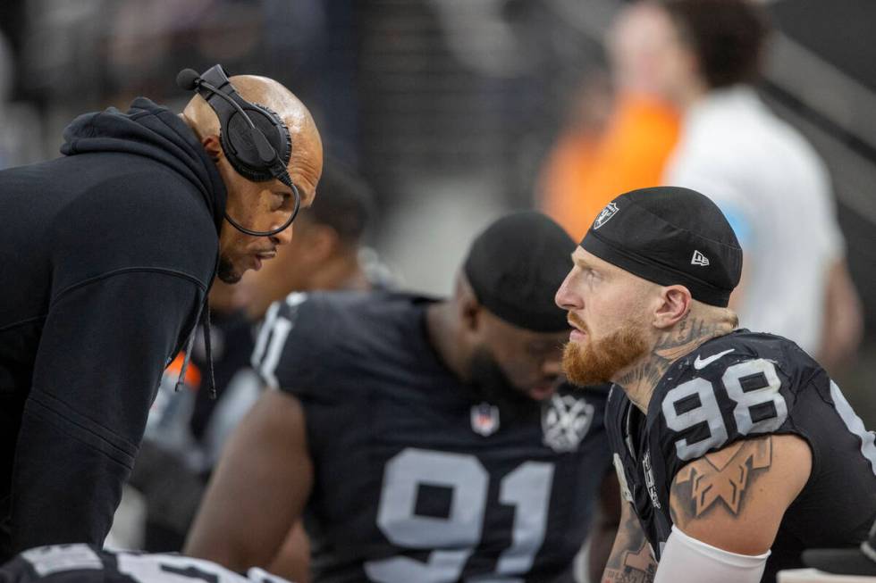 Raiders head coach Antonio Pierce speaks with Raiders defensive end Maxx Crosby (98) on the sid ...