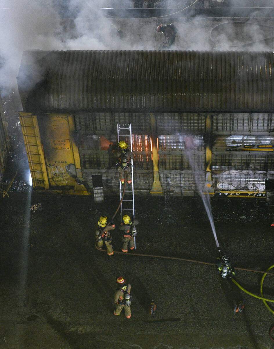 Firefighters work to put out a fire in a railcar carrying autos Friday, November 22, 2024, near ...