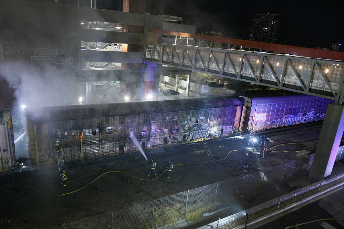 Firefighters work to put out a fire in a railcar carrying autos Friday, November 22, 2024, near ...