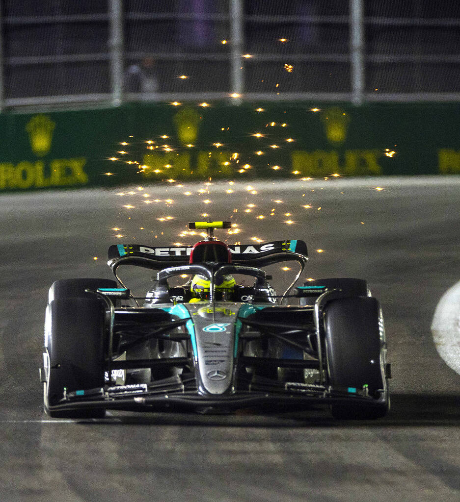 Mercedes driver Lewis Hamilton sends some sparks flying while in the final turn on the track du ...