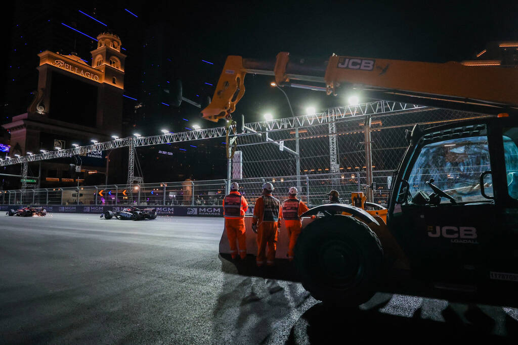 Formula 1 workers watch drivers zoom by during the Formula 1 Las Vegas Grand Prix on the Strip ...