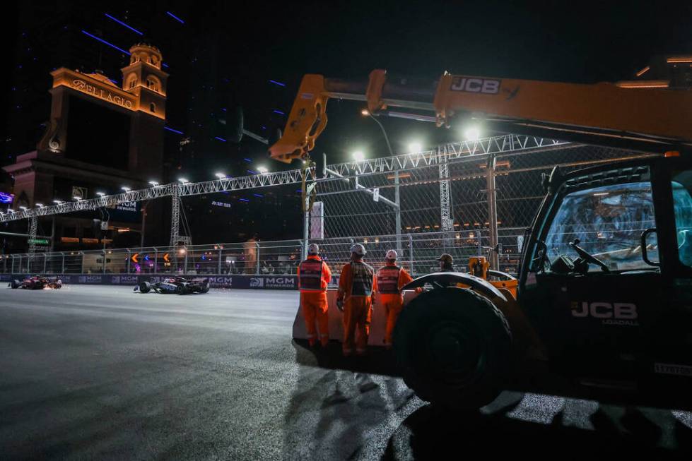 Formula 1 workers watch drivers zoom by during the Formula 1 Las Vegas Grand Prix on the Strip ...