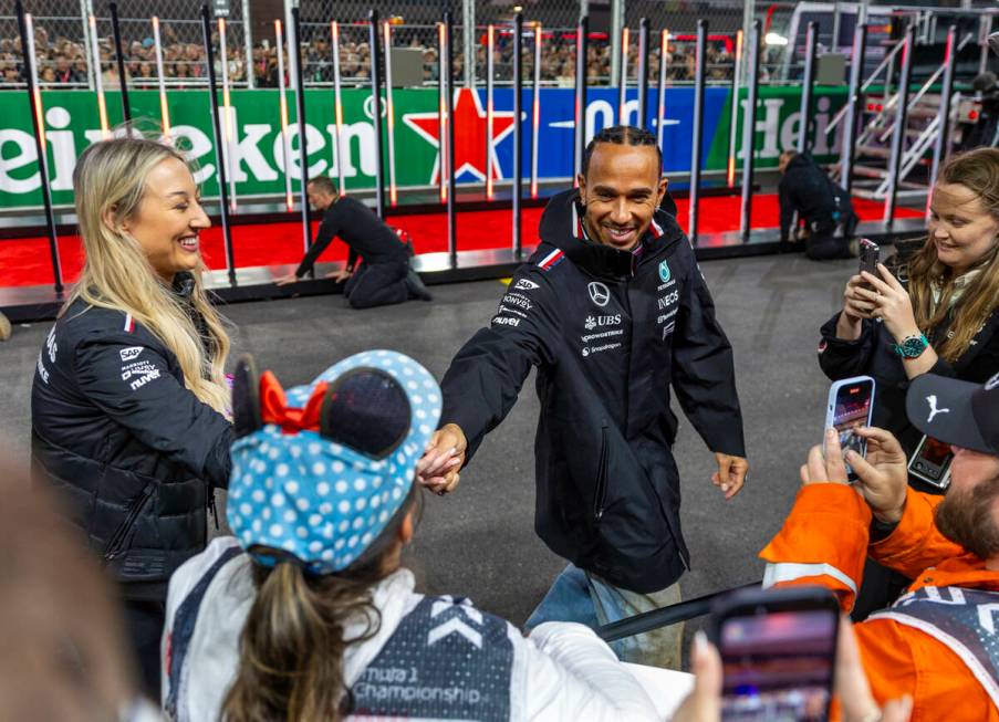 Mercedes driver Lewis Hamilton signs an autograph for a fan on the track after he's introduced ...