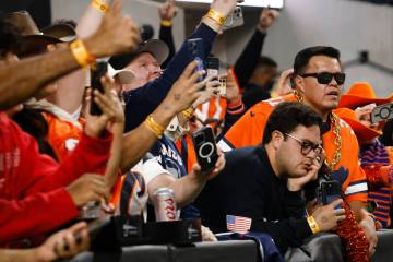 Denver Broncos fans celebrate as their team scored a touchdown as a Raiders fan, right, looks d ...