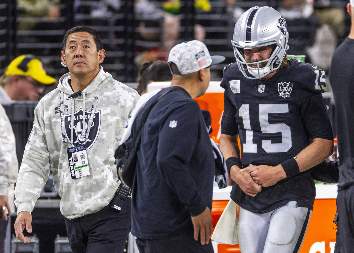 Raiders quarterback Gardner Minshew (15) is escorted off the field by team orthopaedic surgeon ...