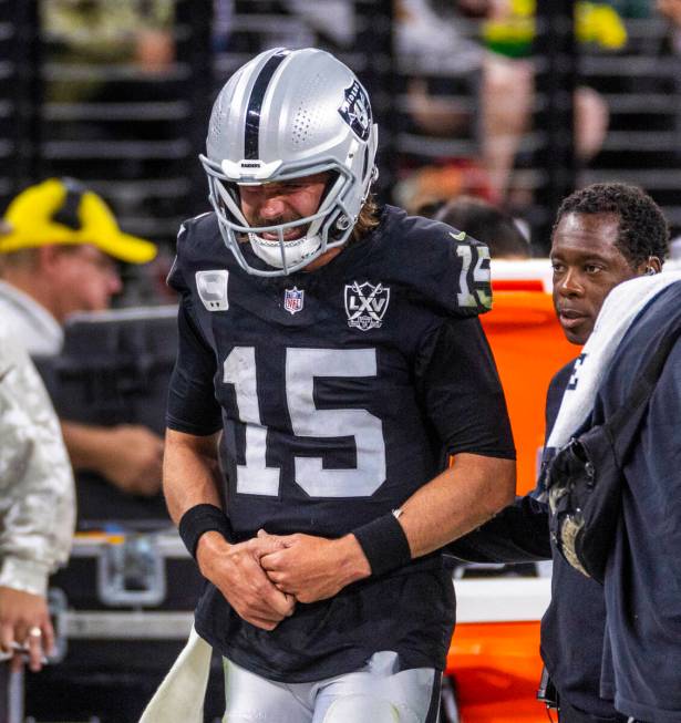 Raiders quarterback Gardner Minshew (15) is escorted off the field after a sack with a hand inj ...