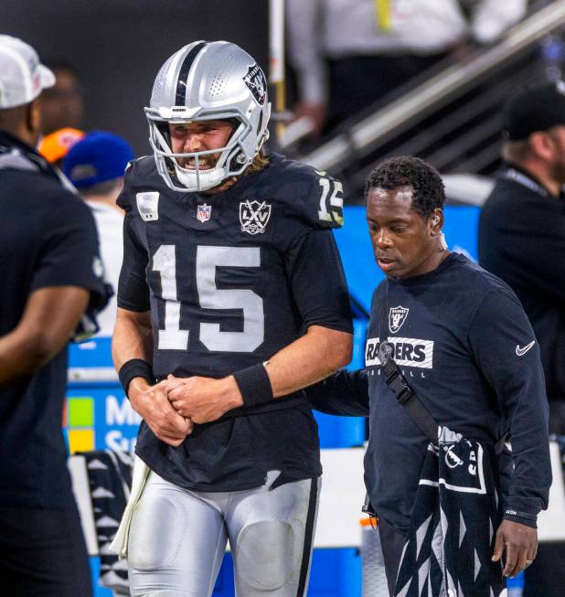 Raiders quarterback Gardner Minshew (15) is escorted off the field after a sack with a hand inj ...