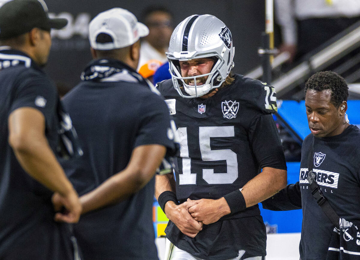 Raiders quarterback Gardner Minshew (15) is escorted off the field after a sack with a hand inj ...