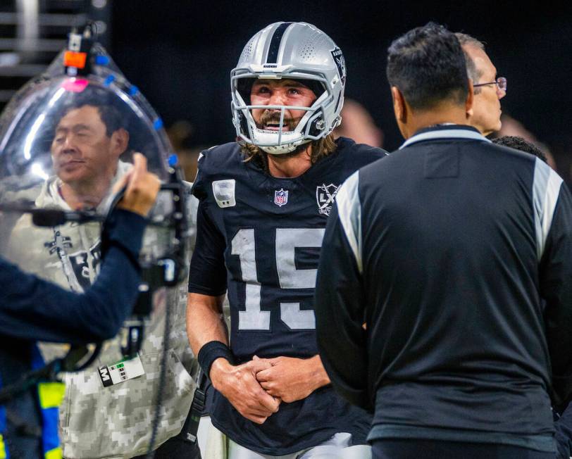 Raiders quarterback Gardner Minshew (15) is escorted off the field after a sack with a hand inj ...