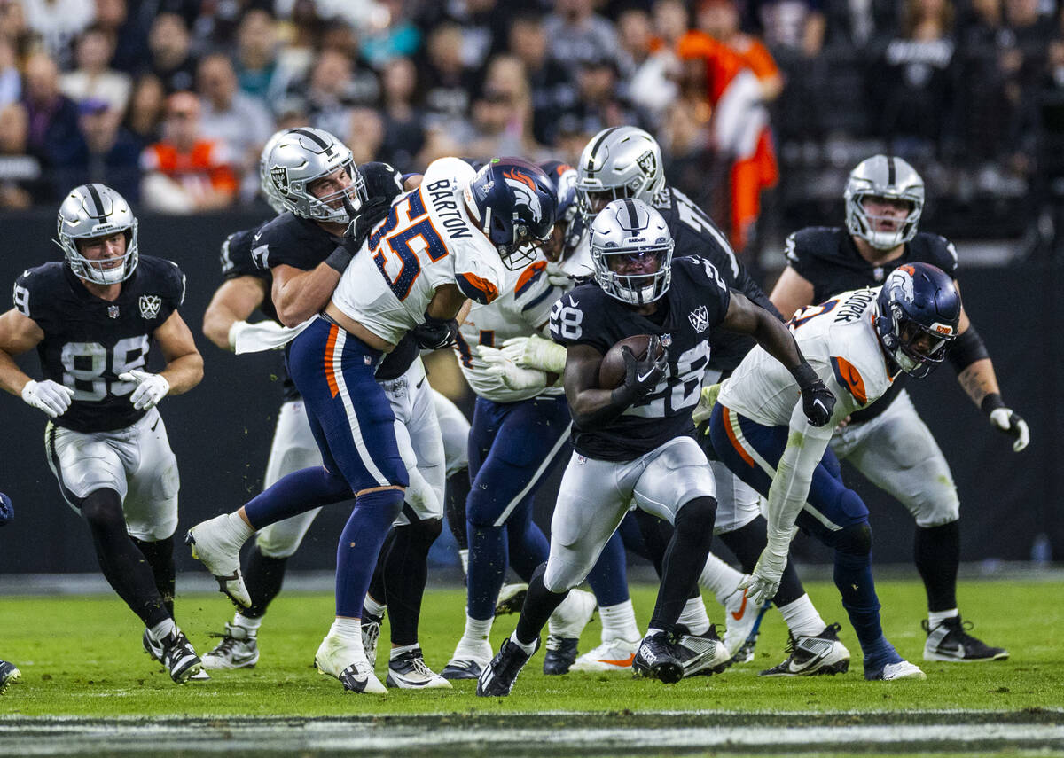 Raiders running back Sincere McCormick (28) break through the line and up the field as Denver B ...