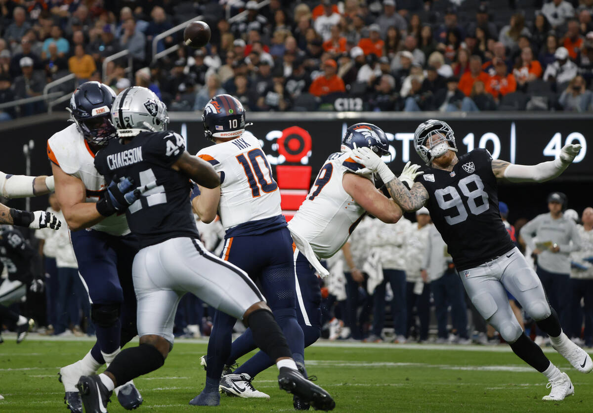 Denver Broncos quarterback Bo Nix (10) throws under pressure from Raiders defensive end K'Lavon ...