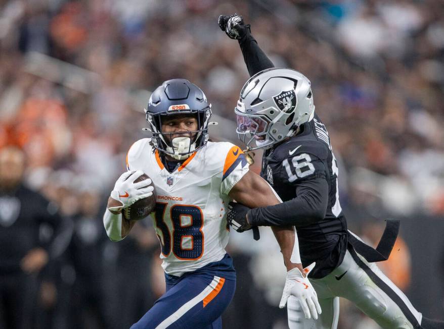 Raiders cornerback Jack Jones (18) attempts to punch the football out of Denver Broncos running ...