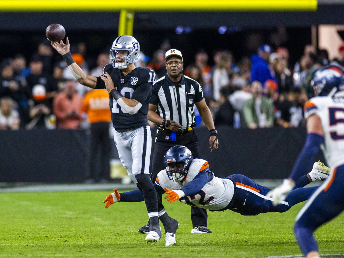 Raiders quarterback Desmond Ridder (10) gets off pass with pressure from Denver Broncos linebac ...