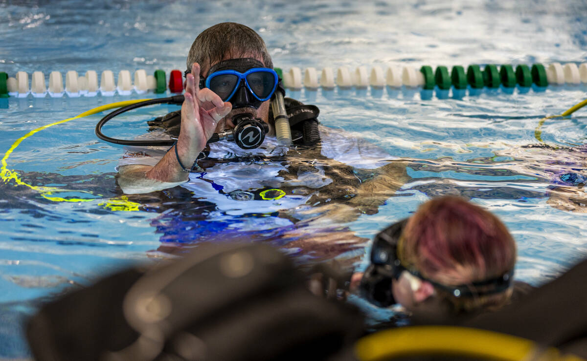 Sin City Scuba diving instructor Curtis Snaper shows hand signals to use underwater during a cl ...