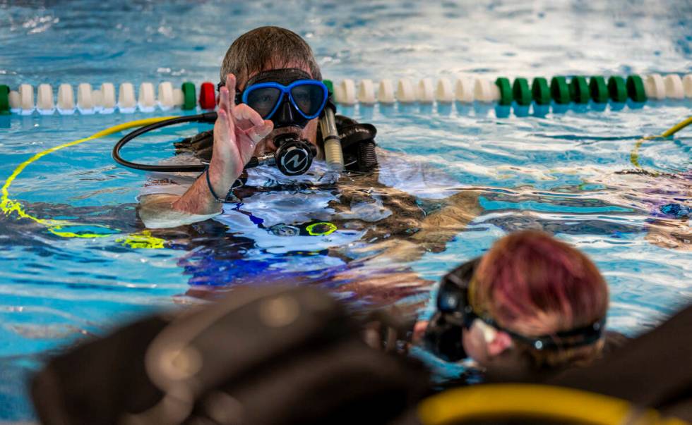 Sin City Scuba diving instructor Curtis Snaper shows hand signals to use underwater during a cl ...