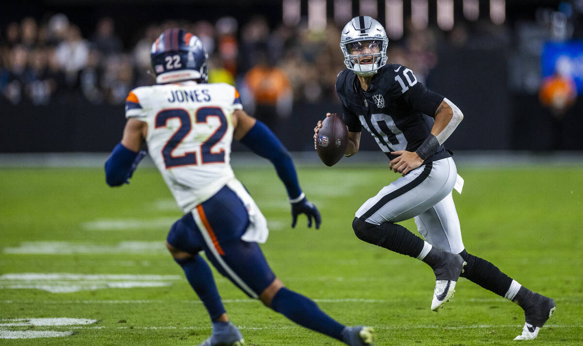 Raiders quarterback Desmond Ridder (10) scrambles to pass as Denver Broncos safety Brandon Jone ...