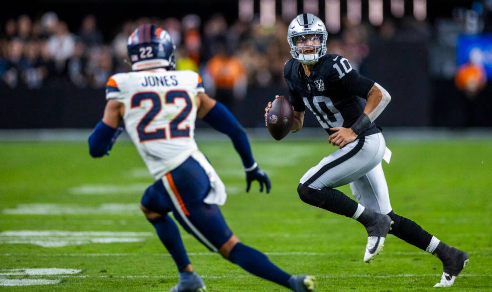 Raiders quarterback Desmond Ridder (10) scrambles to pass as Denver Broncos safety Brandon Jone ...