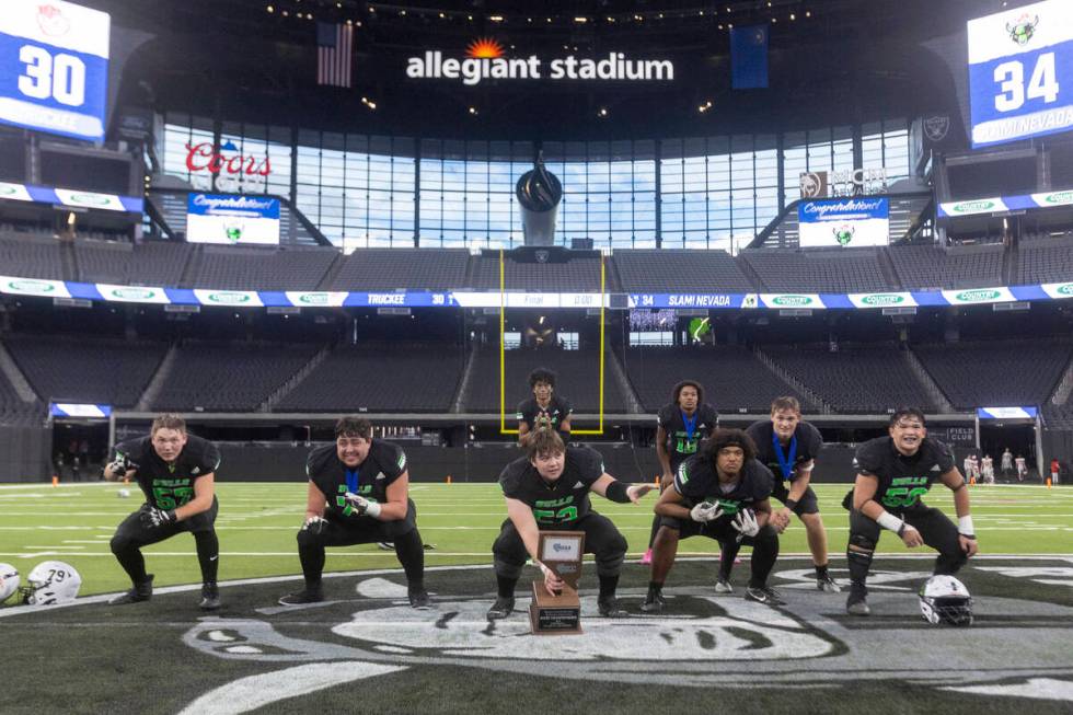 The SLAM Academy offensive line pose at the center of the field with the trophy after winning t ...