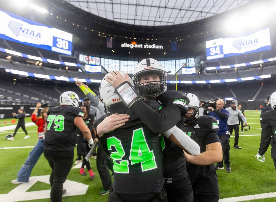 SLAM Academy sophomore Greg Waters-Cortez (24) and quarterback Mark Schramm, right, hug each ot ...