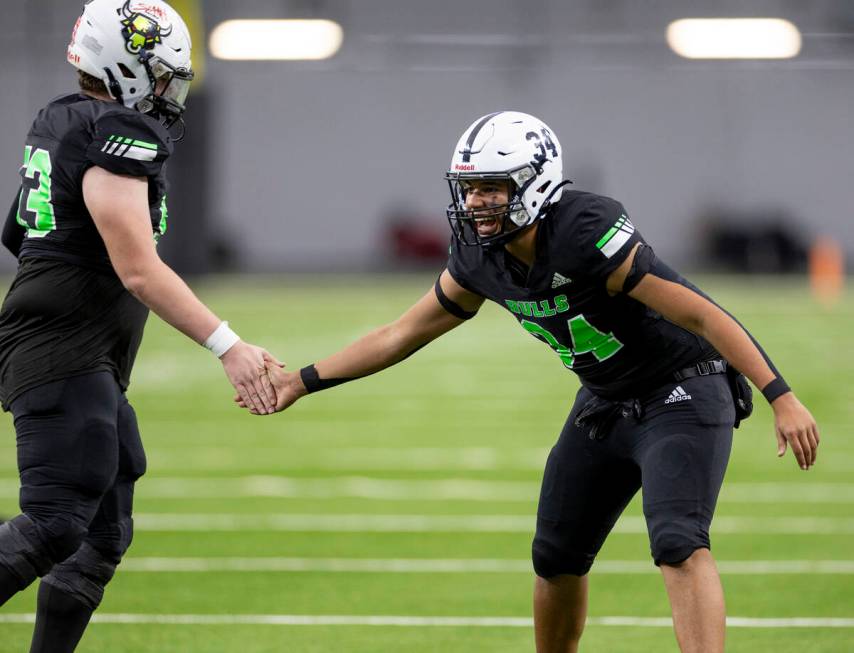 SLAM Academy freshman Czar Soto (34) high-fives his teammates after a scoring drive during the ...