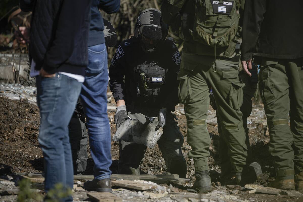 Police bomb squad officers collect the pieces of a rocket fired from Lebanon that landed in a b ...