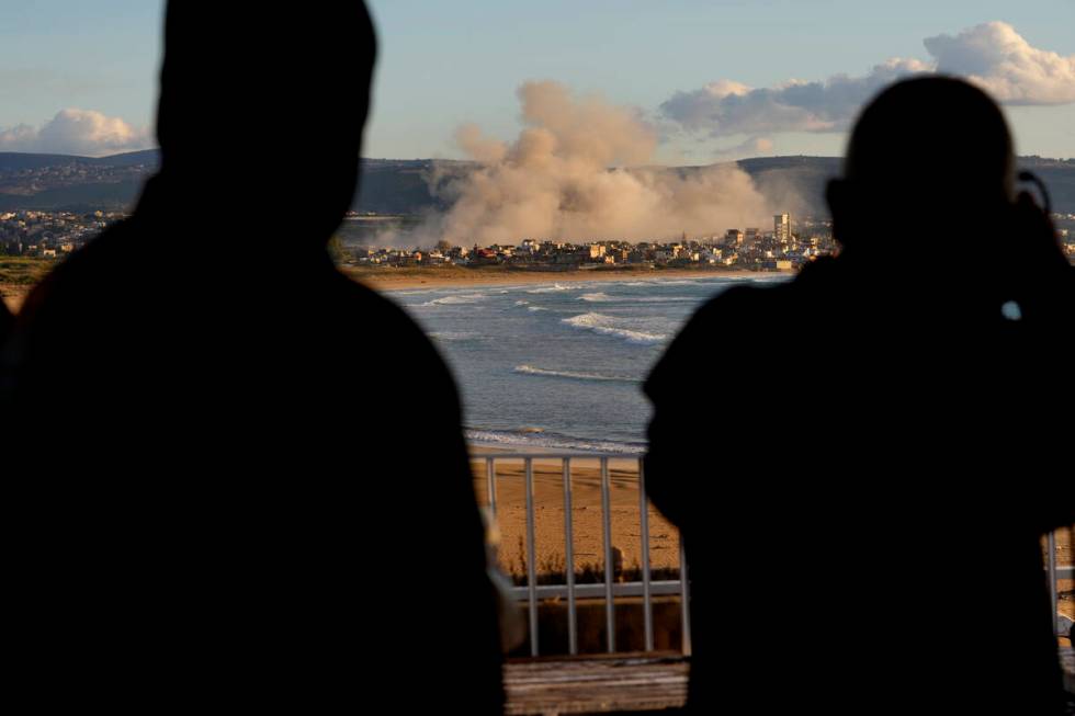 Journalists watch the smoke rising between buildings hit in Israeli airstrikes near the Palesti ...