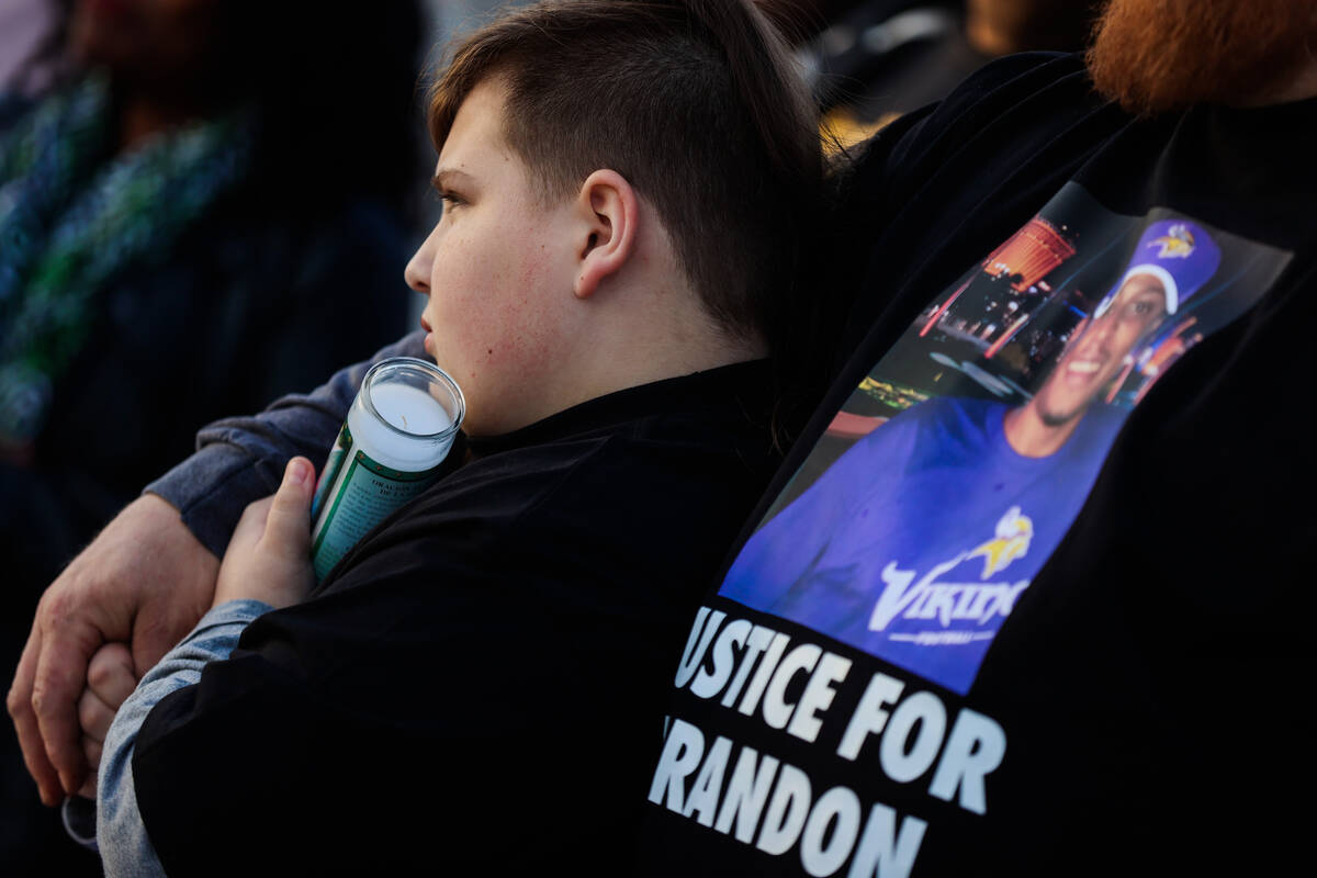 Elwood Pender, 12, leans into his dad, Lowell, during a vigil for Brandon Durham, who was shot ...