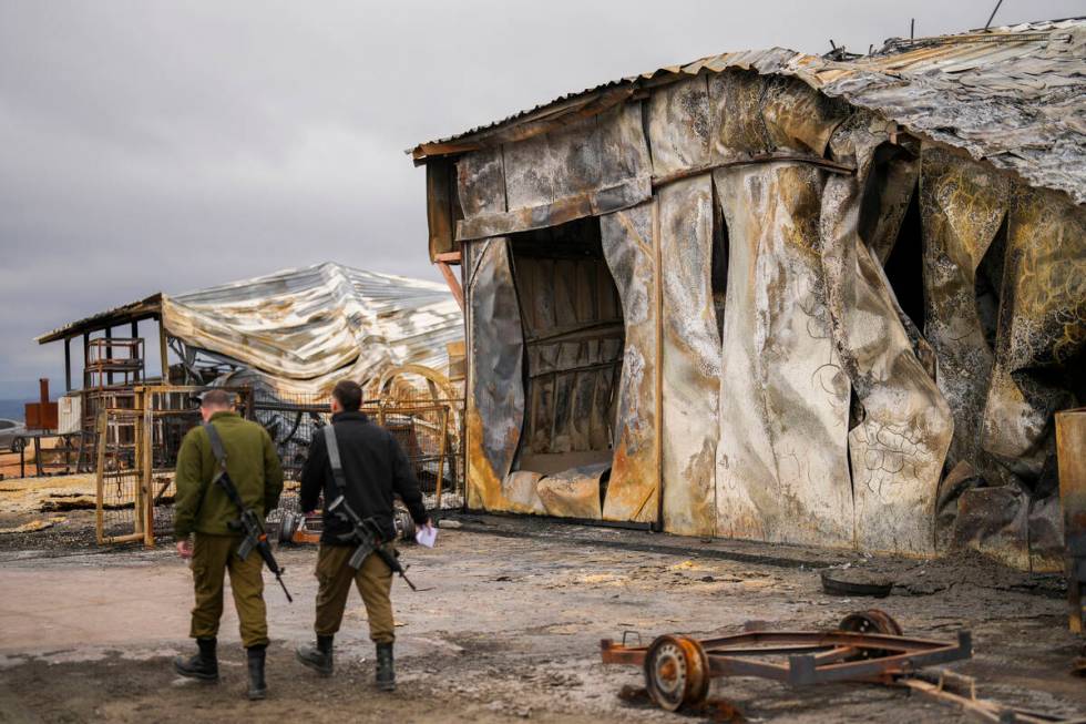 Israel soldiers walk next to a damaged animal farm hit by a rocket fired from Lebanon in Avivim ...