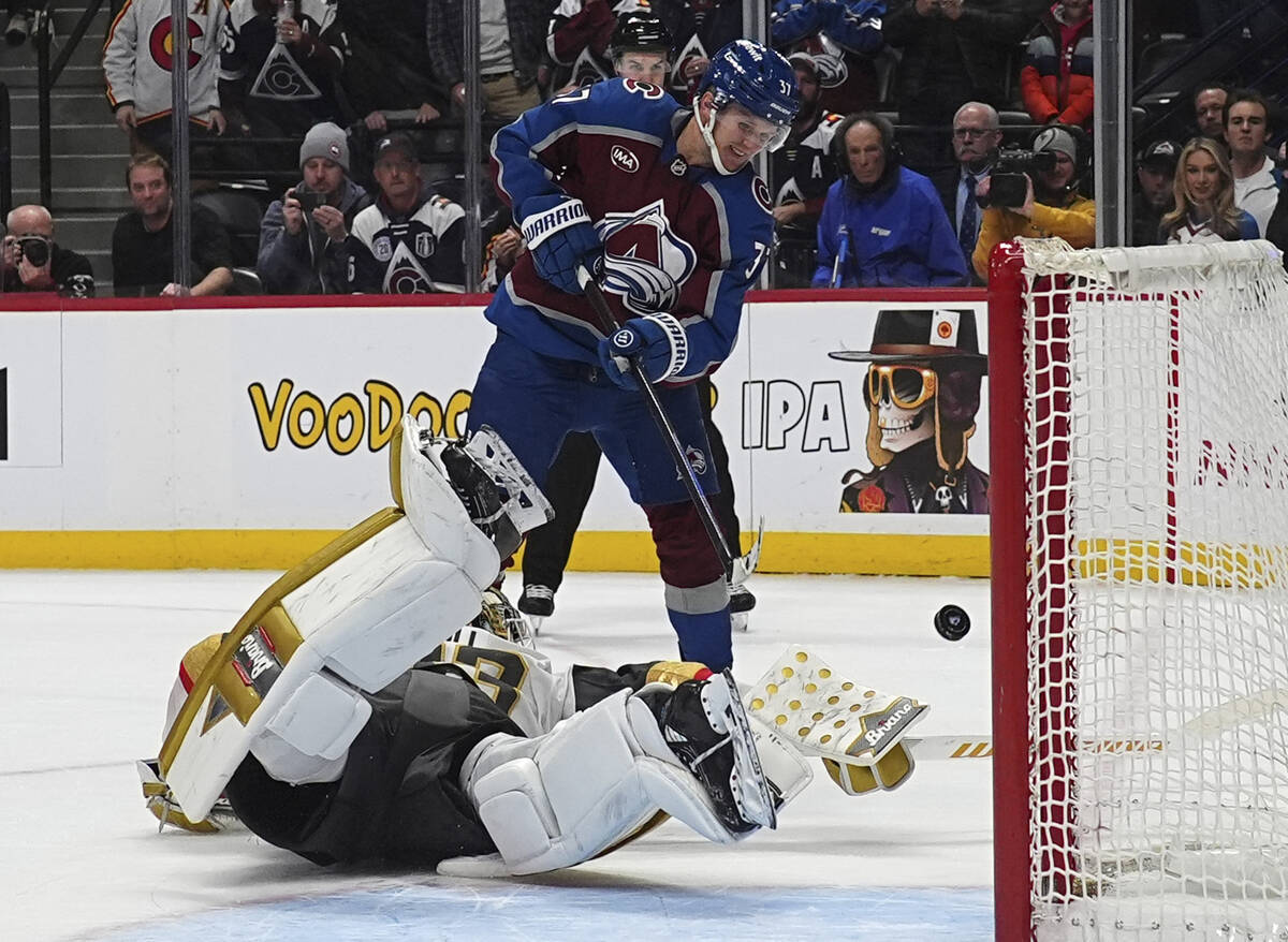 Vegas Golden Knights goaltender Adin Hill, bottom, deflects a shot by Colorado Avalanche center ...