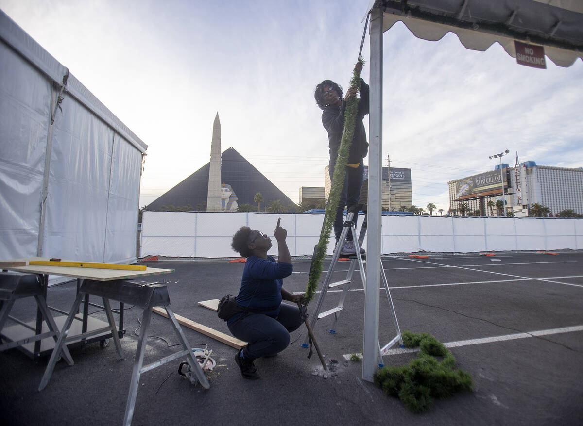 Unique Clemons, left, and Amisah Keden, right, hang garland during setup of Christmas on the St ...