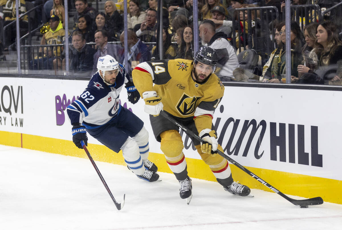 Golden Knights defenseman Nicolas Hague (14) keeps the puck away from Winnipeg Jets right wing ...