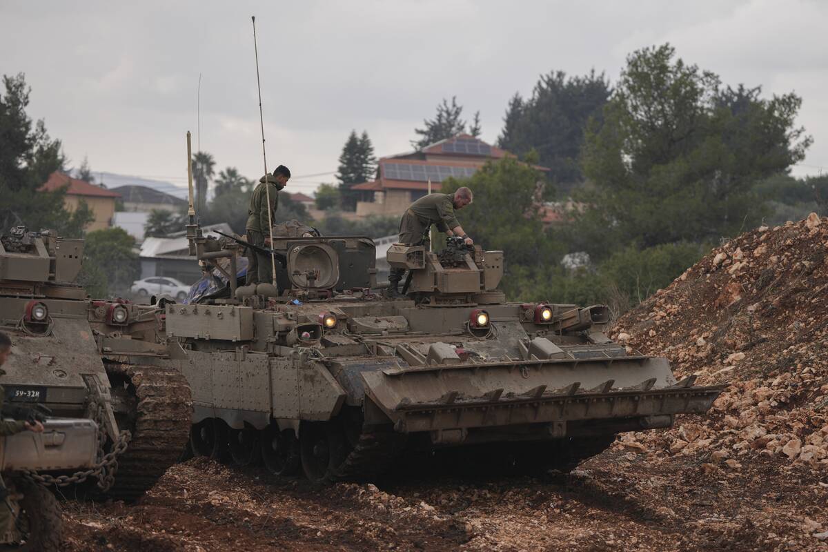 Israeli soldiers stand atop army armoured vehicles outside the agricultural settlement of Avivi ...