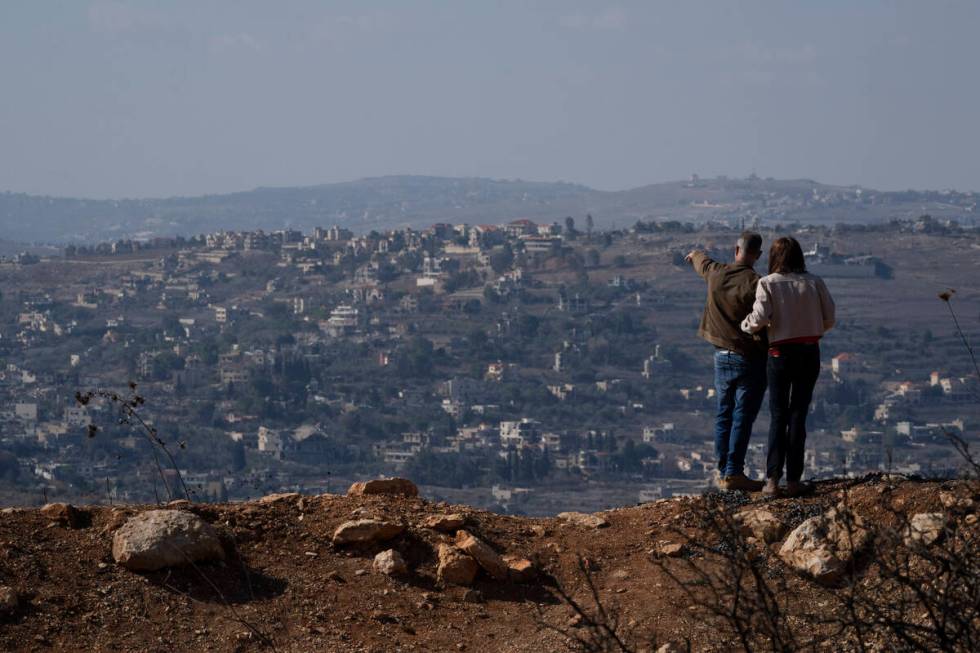 An Israeli couple observe the damaged buildings on a village in southern Lebanon as they stand ...